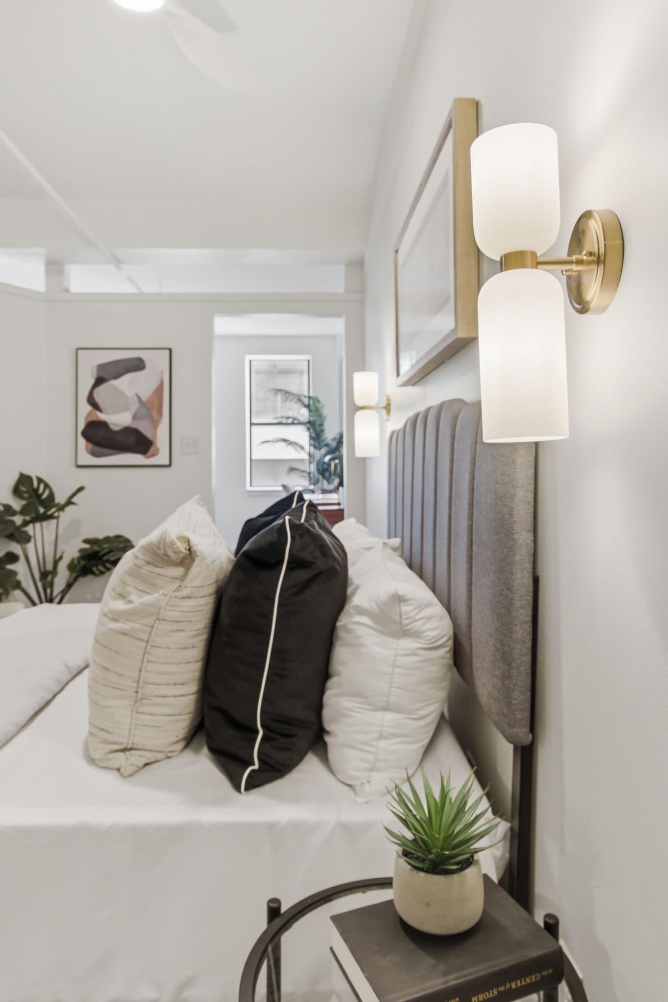 Bedside detail with sconces and pillows against painted walls