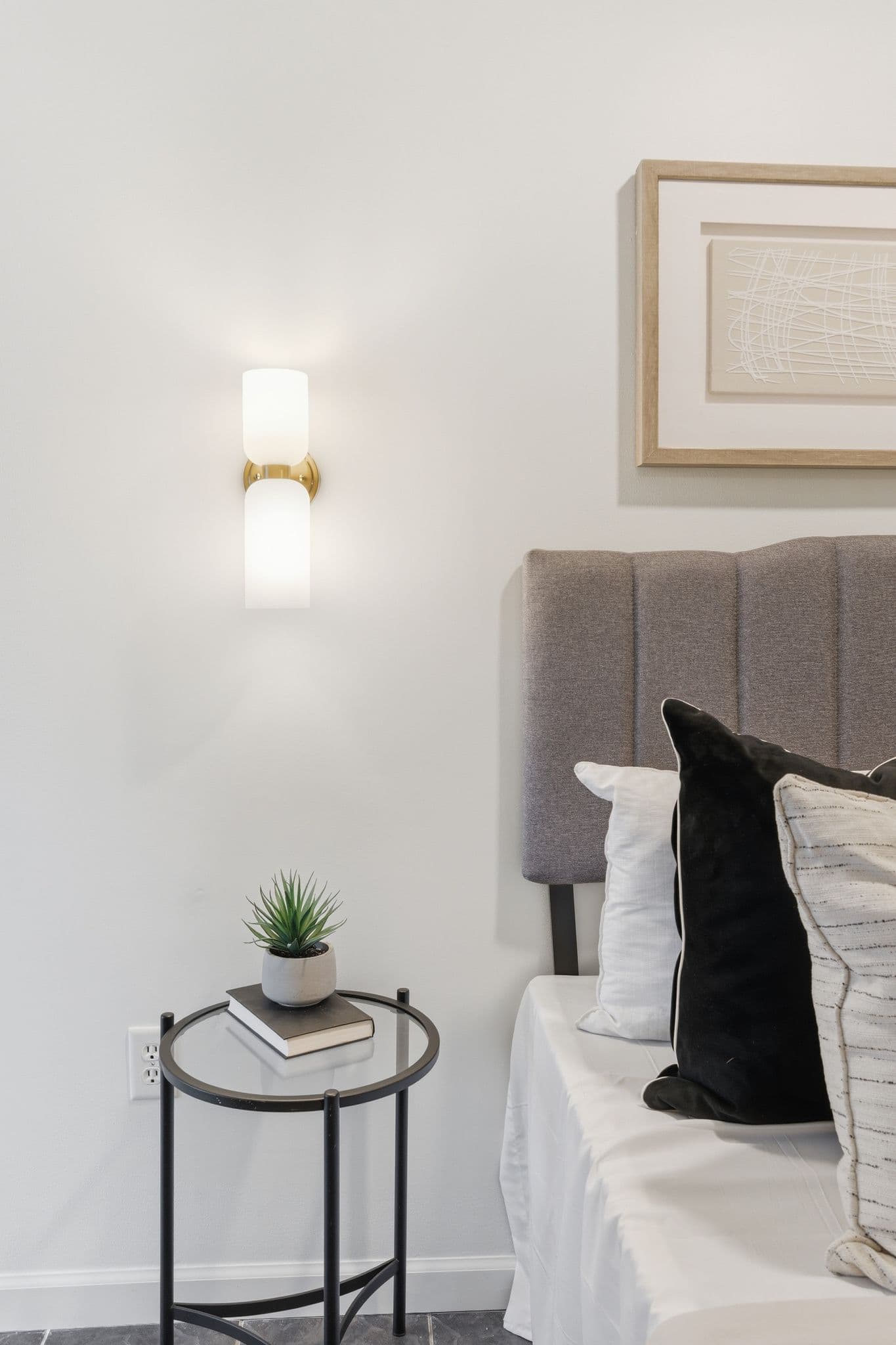 Bedroom detail with sconce, side table, and freshly painted walls